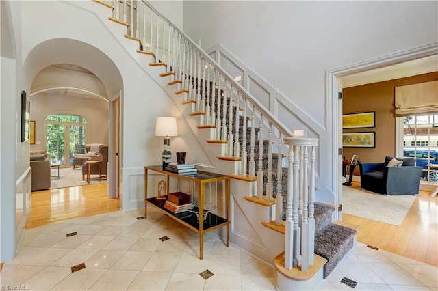 10 Sunfish Pt, Greensboro, NC 27455 - stairs featuring arched walkways, plenty of natural light, a decorative wall, tile patterned floors, and a wainscoted wall