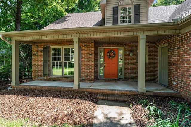 4335 Clovelly Dr, Greensboro, NC 27406 - property entrance featuring a porch, roof with shingles, and brick siding