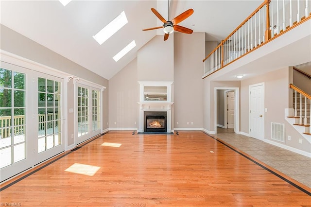 4335 Clovelly Dr, Greensboro, NC 27406 - unfurnished living room featuring high vaulted ceiling, light wood-style floors, a fireplace with flush hearth, ceiling fan, and stairs