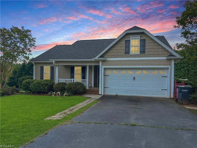view of front of property featuring covered porch, a lawn, a garage, and aphalt driveway