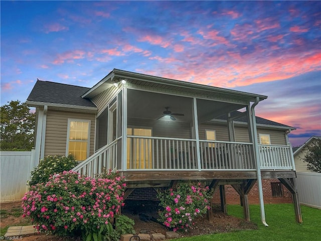 back of property at dusk with fence and a sunroom