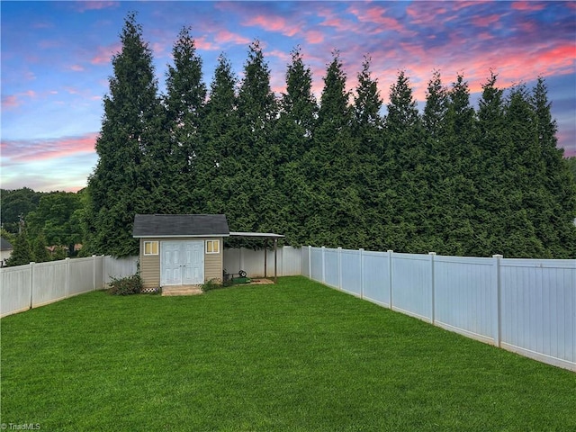 yard at dusk featuring a storage unit, an outdoor structure, a fenced backyard, and a carport