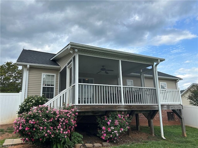 exterior space featuring roof with shingles, ceiling fan, fence, and a sunroom