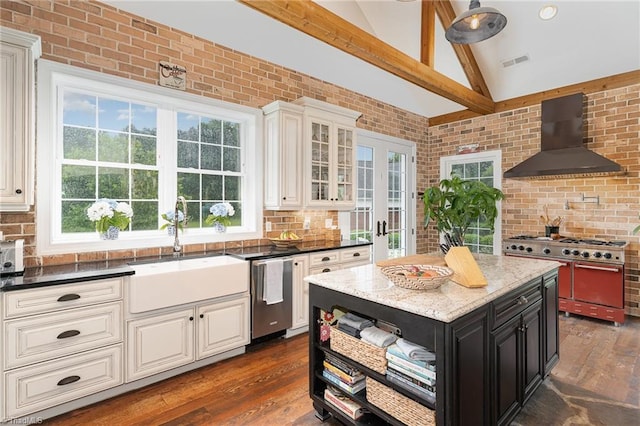 2733 Nebo Rd, East Bend, NC 27018 - kitchen with wall chimney exhaust hood, stainless steel appliances, dark cabinets, dark wood-style floors, and brick wall