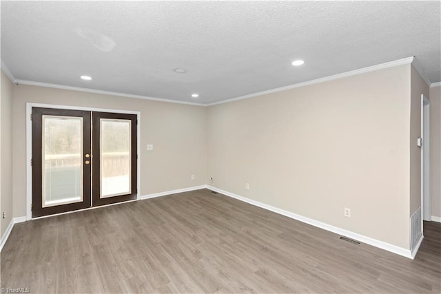 spare room with a textured ceiling, wood-type flooring, ornamental molding, and french doors