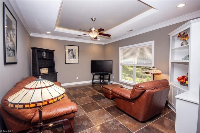 living room with ceiling fan, dark tile patterned flooring, ornamental molding, and a tray ceiling