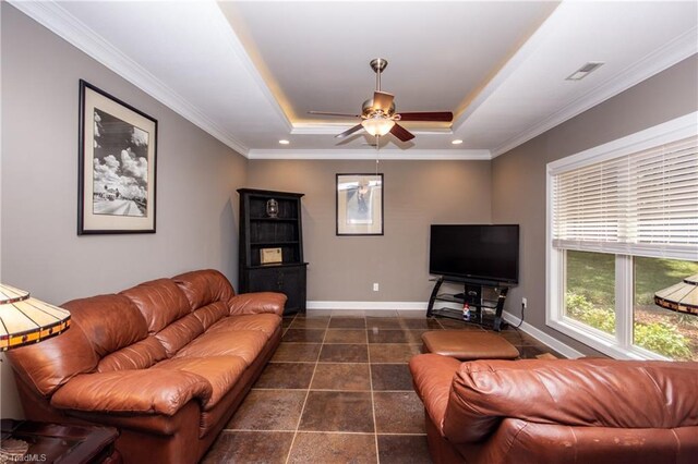 tiled living room with ceiling fan, a tray ceiling, and ornamental molding