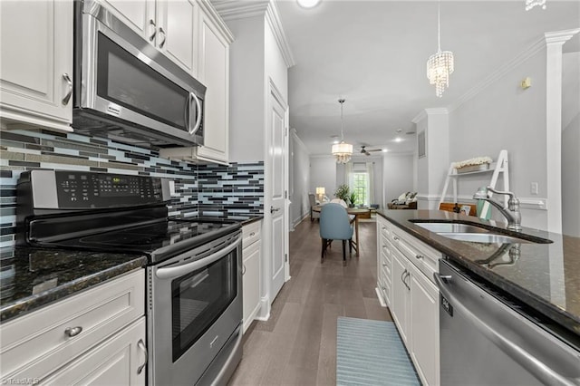 606 Bellemeade St, Greensboro, NC 27401 - kitchen with appliances with stainless steel finishes, a chandelier, white cabinets, tasteful backsplash, and crown molding