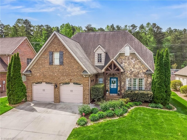 traditional-style home featuring a front yard, a garage, driveway, stone siding, and brick siding