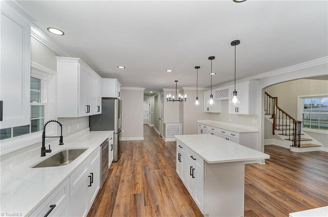 kitchen with white cabinets, wood-type flooring, a center island, and sink