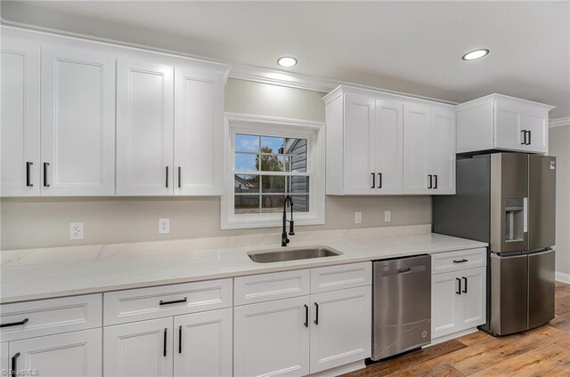 kitchen featuring white cabinets, appliances with stainless steel finishes, crown molding, and sink