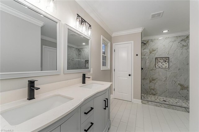 bathroom featuring a tile shower, vanity, and ornamental molding