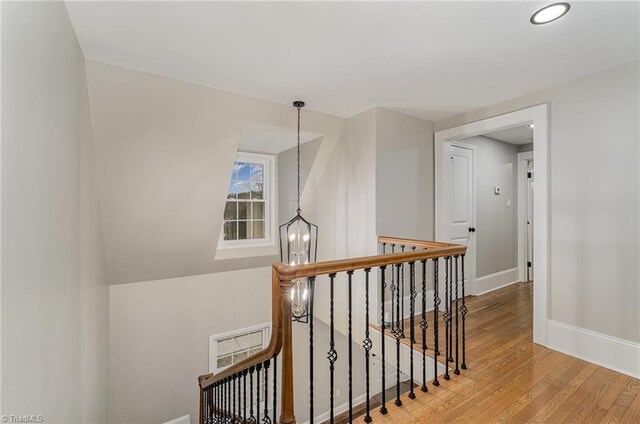 corridor with a notable chandelier and hardwood / wood-style flooring