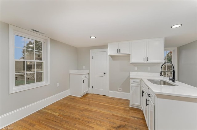 kitchen with white cabinets, light hardwood / wood-style flooring, a healthy amount of sunlight, and sink