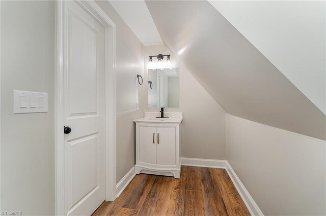 bathroom featuring vanity, wood-type flooring, and vaulted ceiling