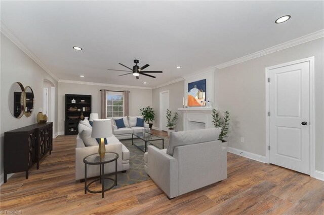 living room with crown molding, a large fireplace, ceiling fan, and dark hardwood / wood-style floors