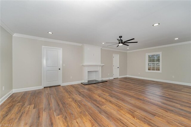 unfurnished living room featuring a fireplace, hardwood / wood-style flooring, ceiling fan, and crown molding