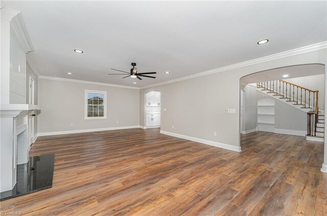 unfurnished living room with a fireplace, ceiling fan, crown molding, and hardwood / wood-style flooring