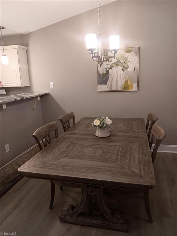 dining space with a chandelier, dark hardwood / wood-style flooring, and vaulted ceiling