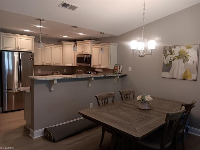 kitchen with a kitchen bar, kitchen peninsula, stainless steel appliances, and hanging light fixtures