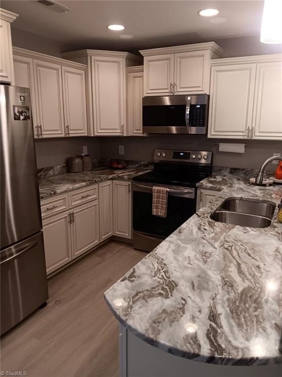 kitchen featuring sink, white cabinets, stainless steel appliances, and light wood-type flooring