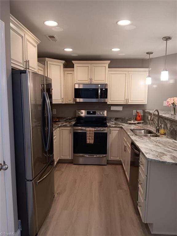 kitchen with sink, light hardwood / wood-style flooring, pendant lighting, and appliances with stainless steel finishes