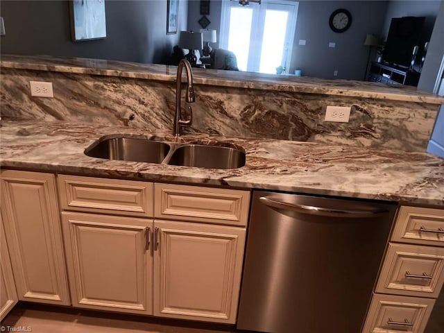 kitchen featuring light stone counters, dishwasher, and sink