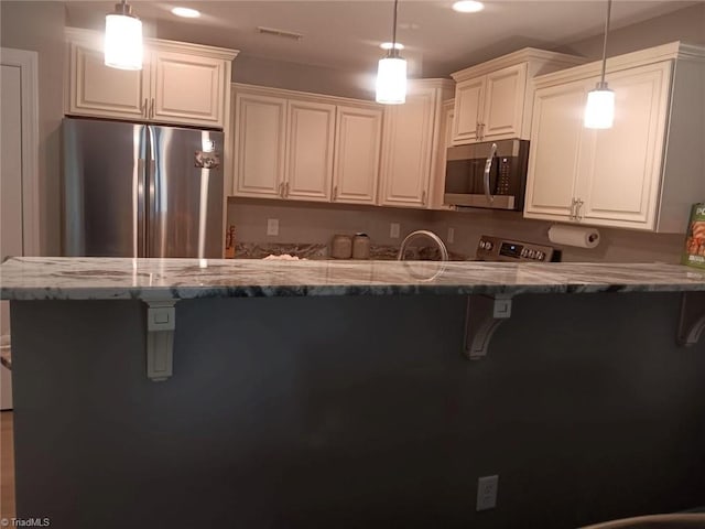 kitchen featuring light stone countertops, kitchen peninsula, pendant lighting, white cabinets, and appliances with stainless steel finishes