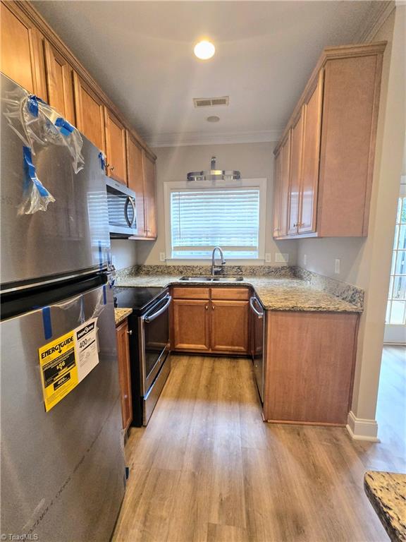 kitchen featuring stainless steel appliances, a healthy amount of sunlight, sink, and light hardwood / wood-style flooring