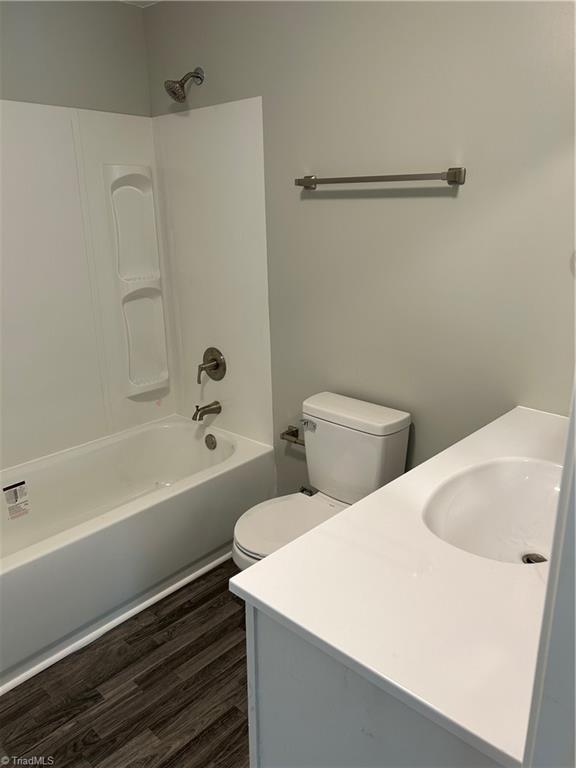 full bathroom with vanity, toilet, hardwood / wood-style flooring, and shower / tub combination