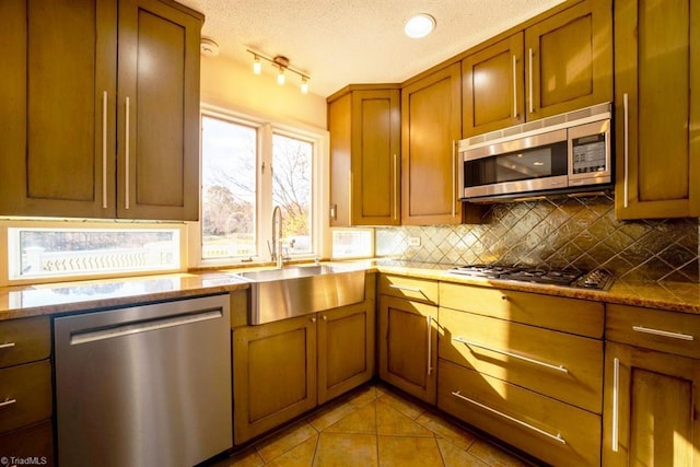 kitchen with tasteful backsplash, a textured ceiling, stainless steel appliances, sink, and light tile patterned flooring