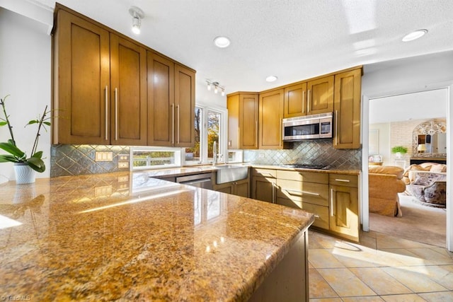 kitchen with kitchen peninsula, appliances with stainless steel finishes, tasteful backsplash, and light tile patterned floors