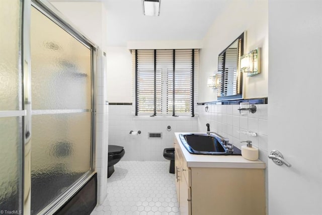 bathroom with walk in shower, vanity, tile walls, tile patterned flooring, and toilet