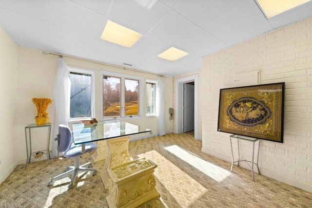 office featuring light carpet, a drop ceiling, and brick wall