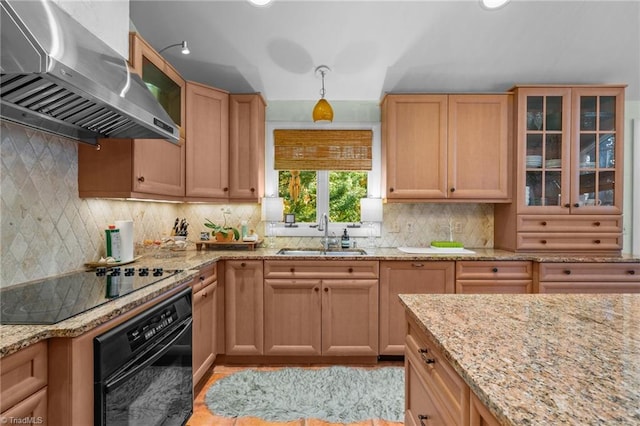 kitchen with black appliances, sink, exhaust hood, and light stone counters