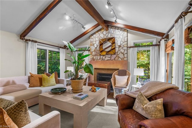 sunroom with lofted ceiling, track lighting, and a stone fireplace