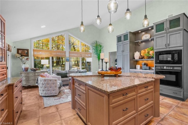 kitchen with black appliances, light tile patterned flooring, light stone counters, and decorative light fixtures