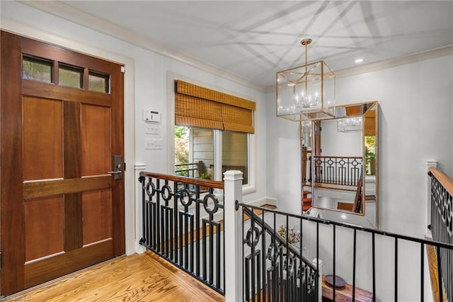 hall with a notable chandelier, ornamental molding, and hardwood / wood-style flooring