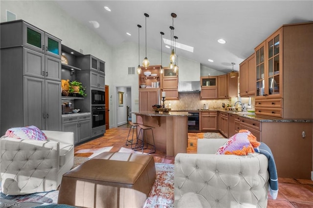 kitchen with black appliances, sink, a center island, decorative light fixtures, and a breakfast bar