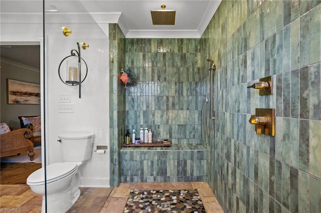 bathroom with tile walls, ornamental molding, a tile shower, and toilet