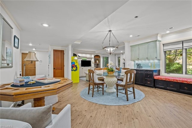 dining space featuring ornamental molding and light hardwood / wood-style flooring