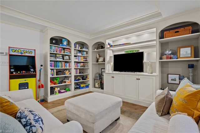 living room with crown molding, built in shelves, and light wood-type flooring