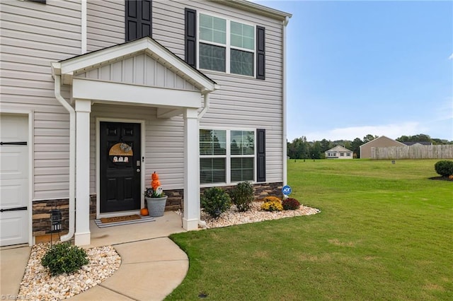 view of exterior entry featuring a garage and a lawn