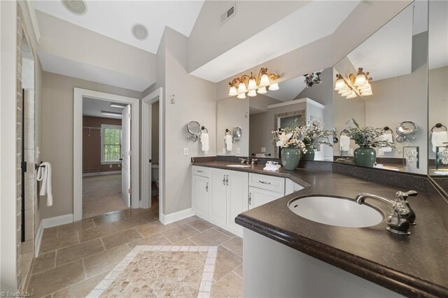 4803 Bluff Run Dr, Greensboro, NC 27455 - bathroom featuring stone tile floors, double vanity, lofted ceiling, and baseboards