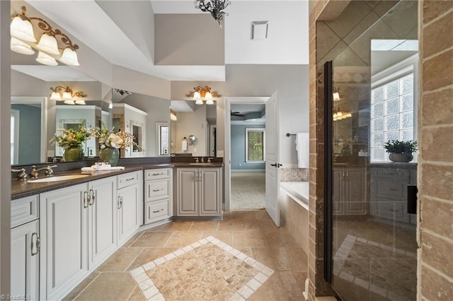 4803 Bluff Run Dr, Greensboro, NC 27455 - bathroom featuring double vanity, a bath, stone tile floors, a tile shower, and baseboards