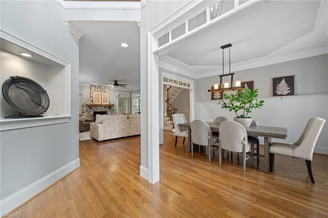 4803 Bluff Run Dr, Greensboro, NC 27455 - dining room featuring stairs, ceiling fan, a fireplace, light wood-type flooring, and a chandelier