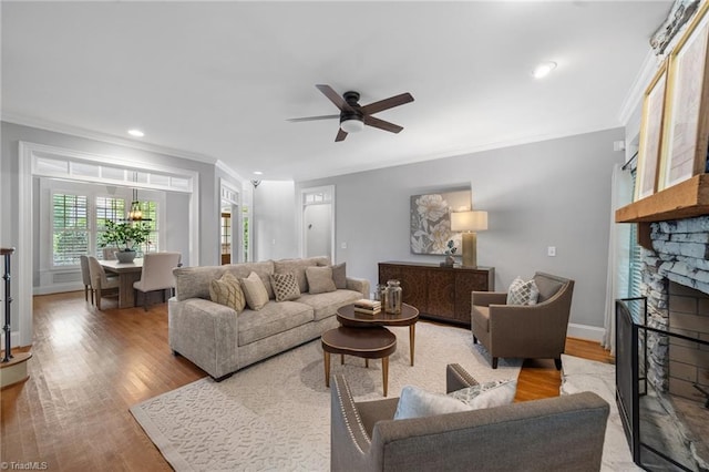 4803 Bluff Run Dr, Greensboro, NC 27455 - living area featuring crown molding, a stone fireplace, ceiling fan, wood finished floors, and baseboards