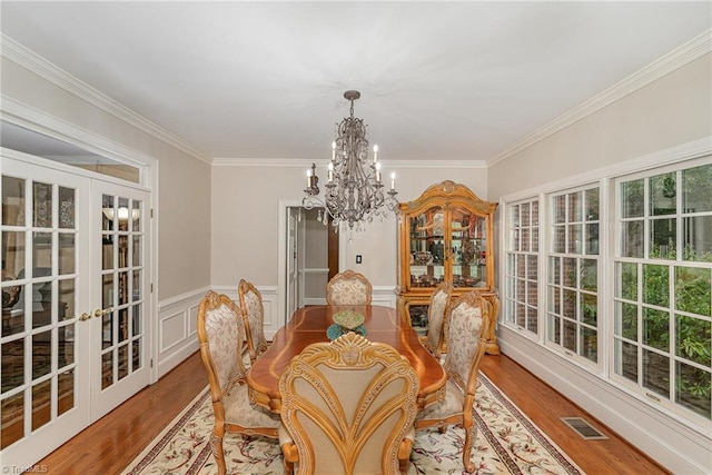 5002 Leadenhall Rd, Oak Ridge, NC 27310 - dining room featuring a chandelier, wood finished floors, crown molding, french doors, and a wainscoted wall