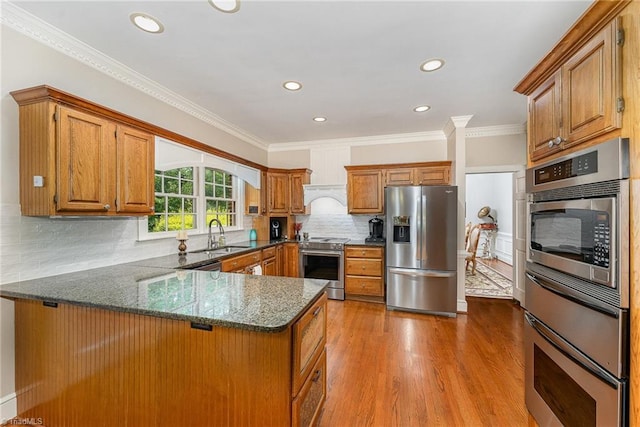 5002 Leadenhall Rd, Oak Ridge, NC 27310 - kitchen with stainless steel appliances, brown cabinetry, a peninsula, dark stone countertops, and recessed lighting