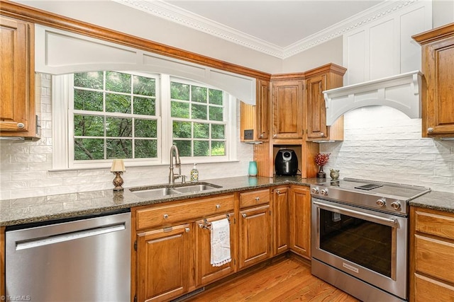 5002 Leadenhall Rd, Oak Ridge, NC 27310 - kitchen featuring stainless steel appliances, a sink, dark stone counters, light wood-style flooring, and brown cabinetry